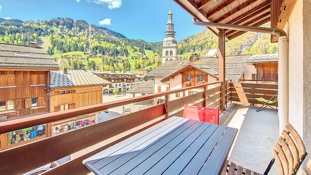 A balcony with a view of a mountain village, wooden buildings, and a church tower. - Apartment 6 pers, 2 bdr, 54 m², garage, La Clusaz (La Clusaz)