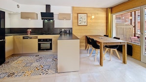 A modern kitchen with a central island, wooden dining table, and chairs. - Apartment 6 pers, 2 bdr, 54 m², garage, La Clusaz (La Clusaz)