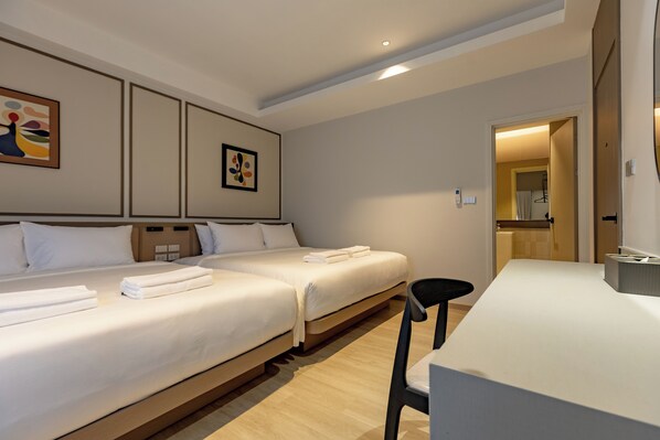 Habitación de hotel con dos camas, un escritorio y una silla. Hay cuadros en la pared.