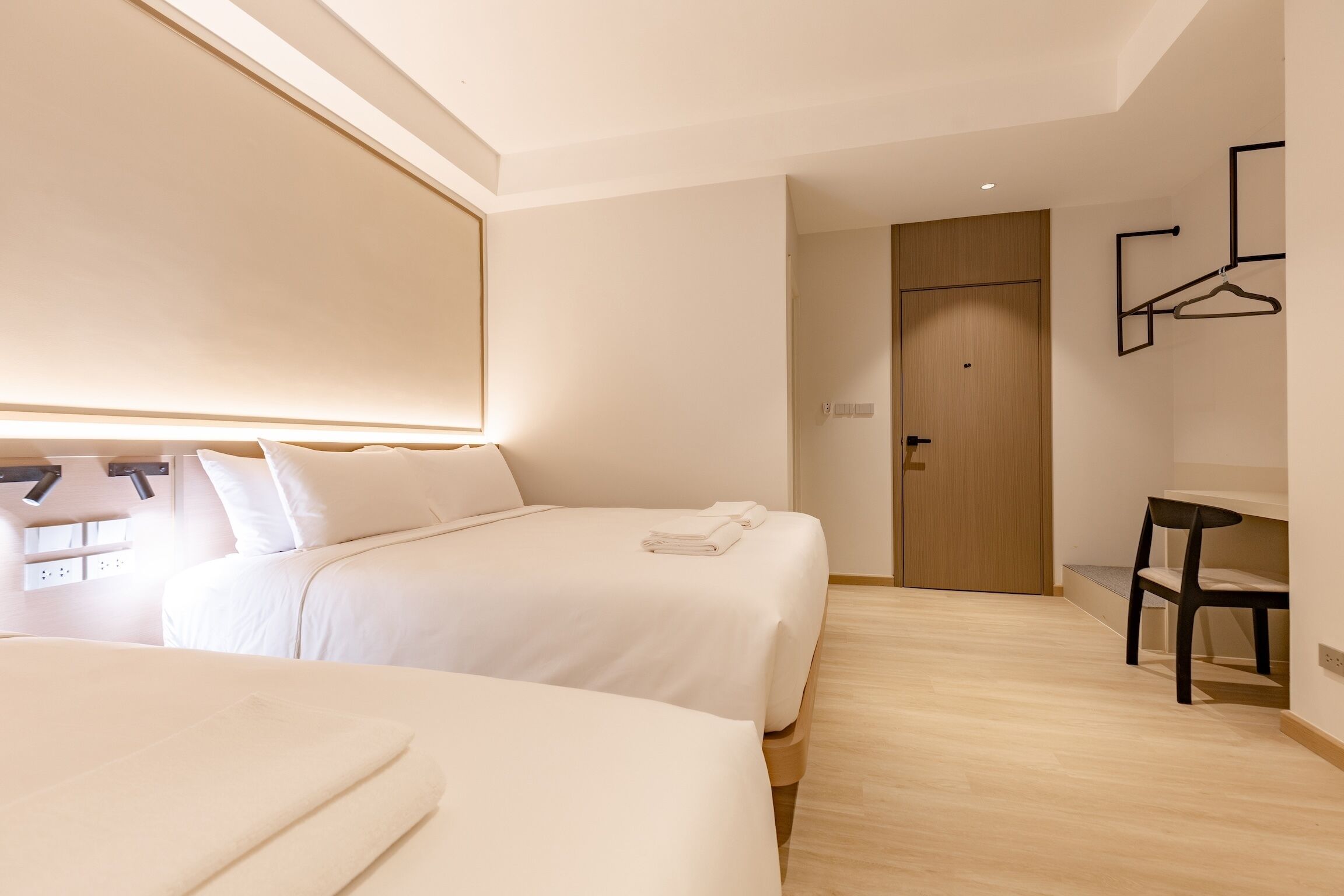 Une chambre d’hôtel moderne avec deux lits, un bureau et une chaise.
