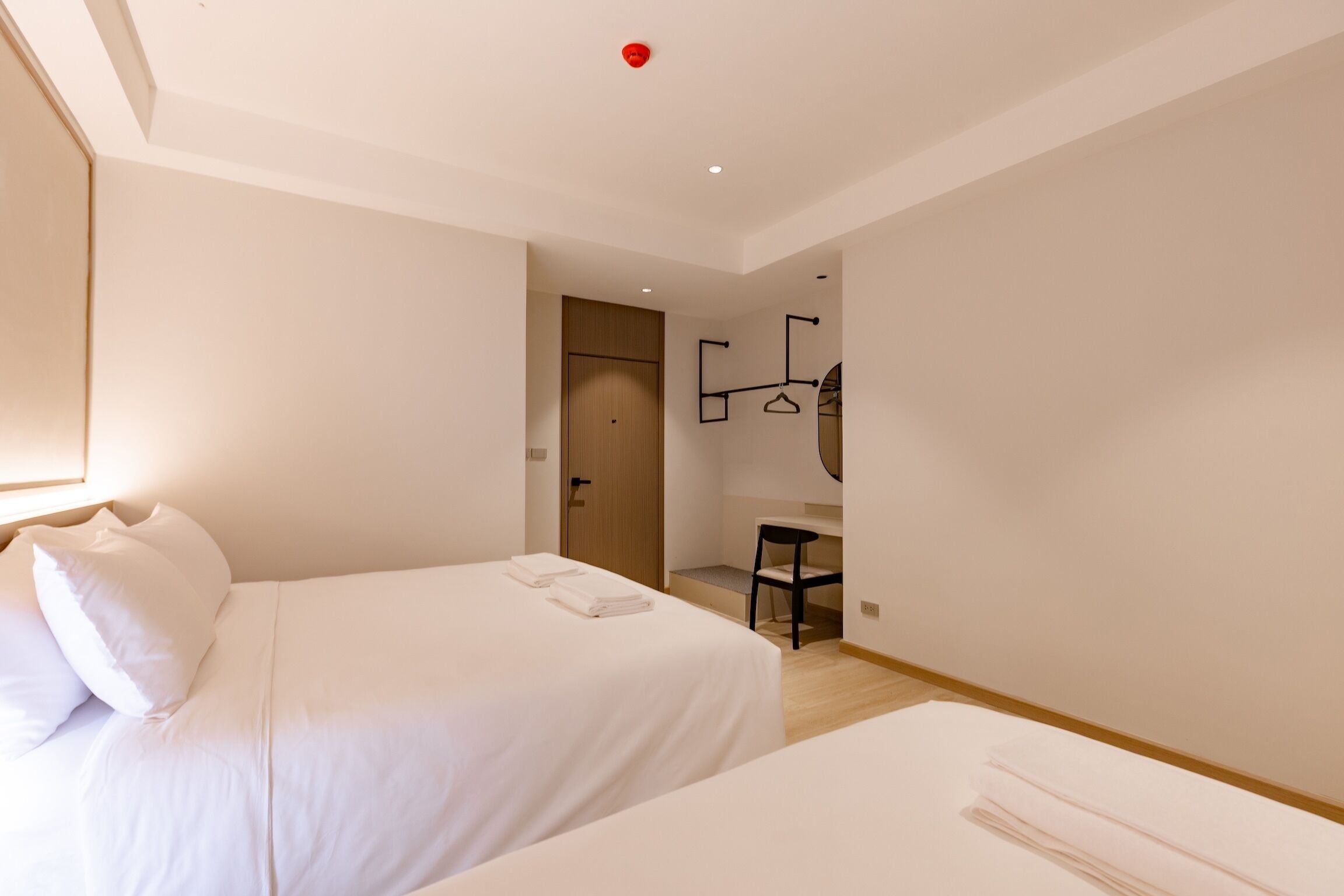 A hotel room with two beds, a desk, and a chair.