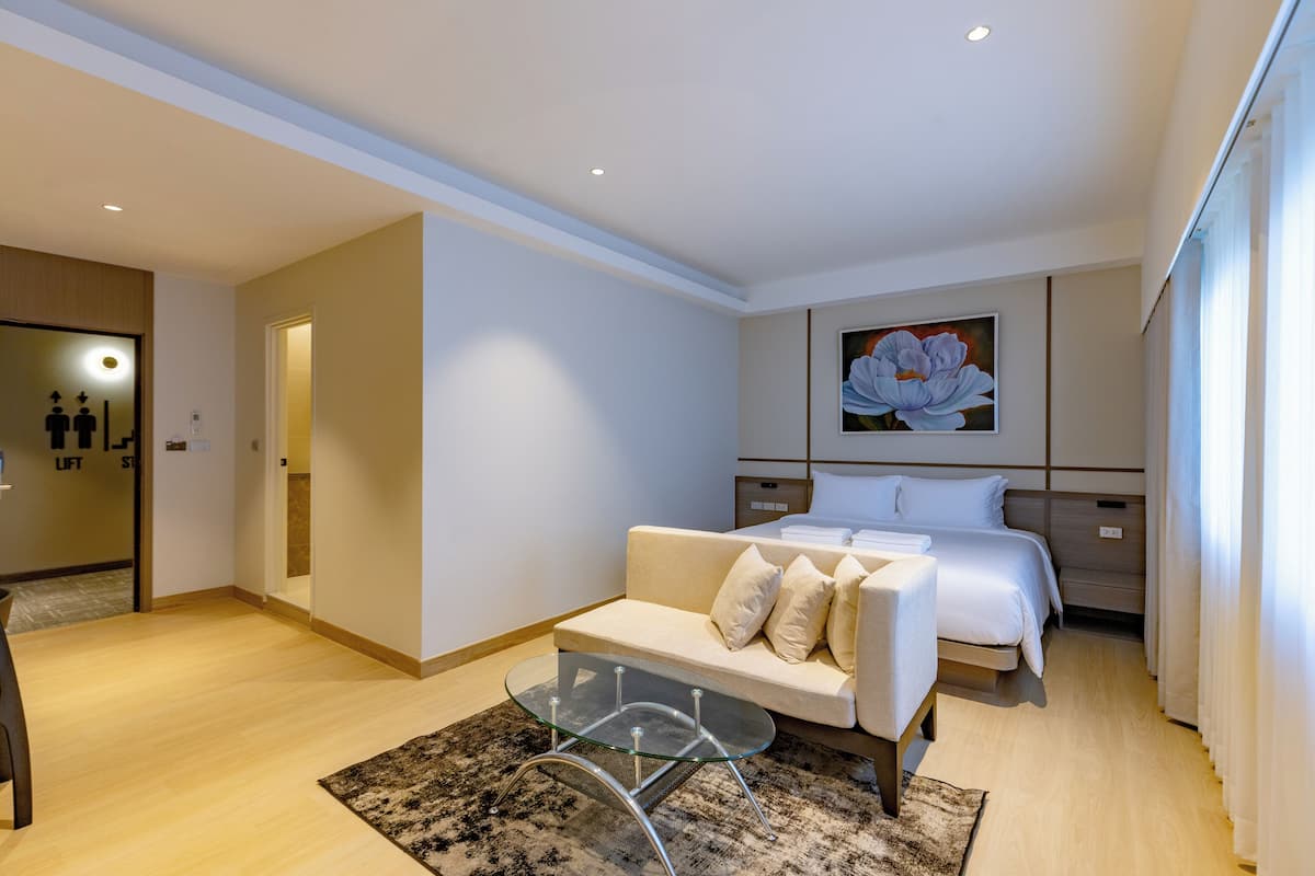 Une chambre d’hôtel moderne, équipée d’un lit, d’un canapé, d’une table basse en verre et d’un tableau au mur.