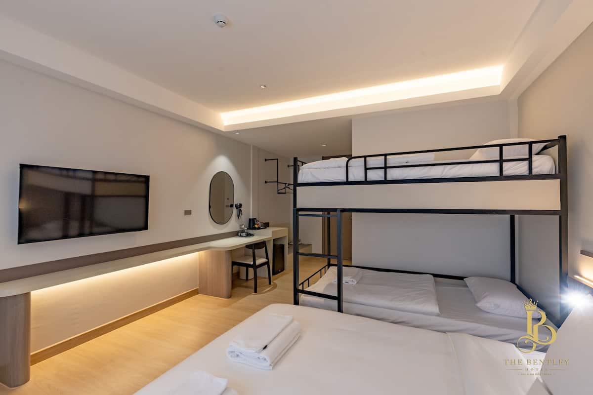 Une chambre d’hôtel avec des lits superposés, un bureau, une chaise, une télévision et un miroir dans la salle de bain.