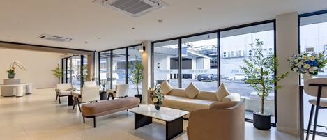 A spacious lobby with a sofa, chairs, a coffee table, and potted plants.