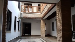 Um pátio com piso em padrão de estrela, varanda de madeira e um pilar de tijolo.