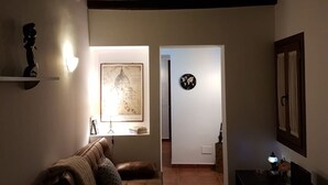 Uma sala de estar aconchegante com um sofá de couro marrom, um mapa emoldurado na parede e um relógio na porta.