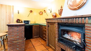 A kitchen with a brick fireplace, a microwave, and a sink. - Charming House in Albaicín, Granada (Granada)