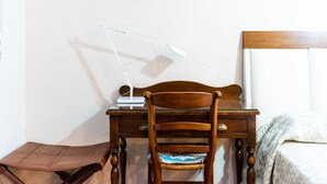 A wooden desk with a lamp, a chair, and a bed in a room with white walls. - Charming House in Albaicín, Granada (Granada)