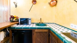 A compact kitchen with a microwave, sink, and wooden cabinet. - Charming House in Albaicín, Granada (Granada)