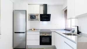 Una cocina compacta equipada con refrigerador, microondas, horno y pileta.