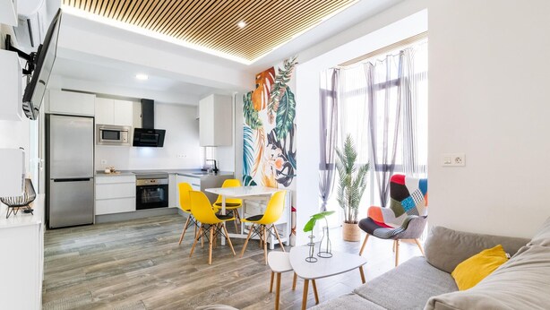 Una cocina moderna con refrigerador, microondas y estufa. Hay un comedor con mesa y sillas.