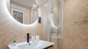 A modern bathroom with a large sink, a mirror, and a shower enclosure.