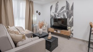 A modern living room with a sofa, a coffee table, a TV, and a decorative wall.