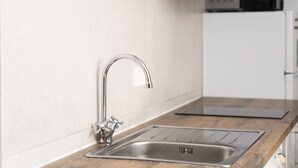 Een moderne keuken met een RVS spoelbak, een zwarte afzuigkap en een magnetron.