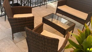 Een terras met rieten meubels, waaronder twee stoelen en een bijzettafeltje.