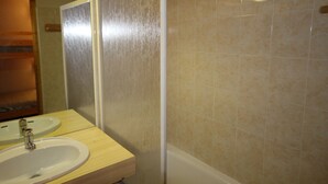 Een badkamer met een wastafel, spiegel en douchecabine.
