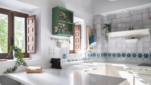 A modern kitchen with white cabinetry, a central island, and a window with brown shutters. - Apartment in Granada with private pool and air conditioning (Granada)