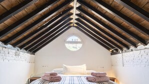 A bedroom with a sloped ceiling, a round window, a bed with striped bedding, and two folded towels on the bed. - Apartment in Granada with private pool and air conditioning (Granada)