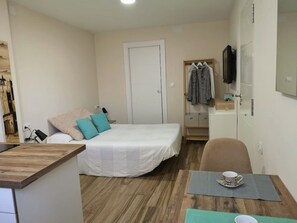 Un dormitorio pequeño y ordenado con cama, mesita de noche y una silla.