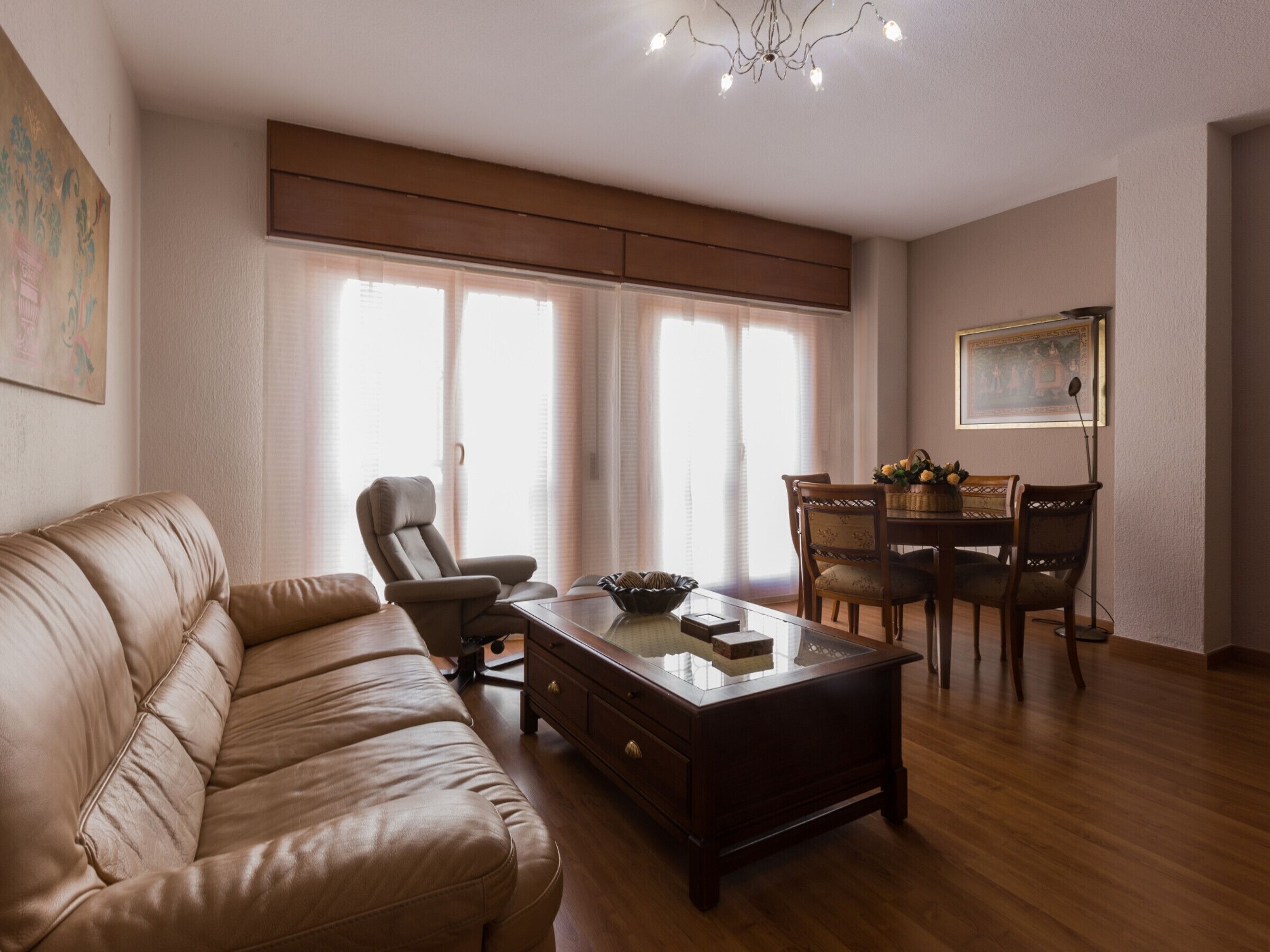 Una sala de estar con un sofá de cuero, una mesa de centro de madera y un comedor con sillas y mesa de madera.