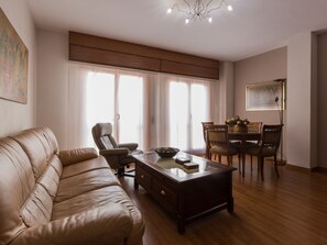 A living room with a leather sofa, a wooden coffee table, and a dining area with wooden chairs and a table. - Charming Apartment in Historical Center Near Granada Cathedral (Granada)