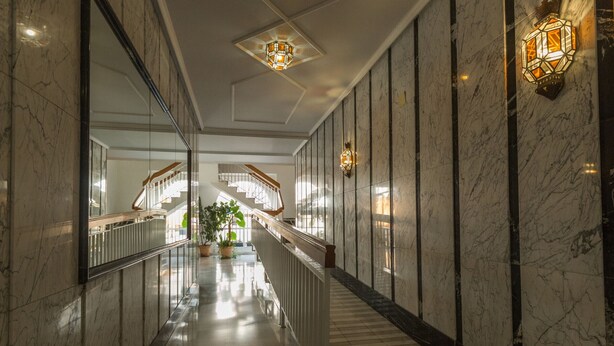 A marble-floored corridor with a staircase, potted plants, and wall-mounted lighting fixtures. - Charming Apartment in Historical Center Near Granada Cathedral (Granada)
