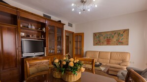 A dining area with a wooden table, chairs, a television, and a painting on the wall. - Charming Apartment in Historical Center Near Granada Cathedral (Granada)