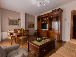 Ein Wohnzimmer mit einem Holzespeisetisch, Stühlen, einem Sofa, einem Couchtisch und einem Fernseher.
