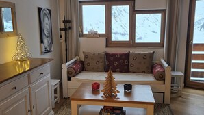 A cozy living room with a sofa, a coffee table, and a bookshelf. - Charming 2-room cabin for 6, ski-in/ski-out access (Avoriaz)