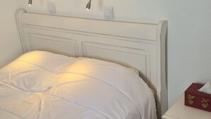 A neatly made bed with a white headboard and a bedside table with a tissue box. - Charming 2-room cabin for 6, ski-in/ski-out access (Avoriaz)