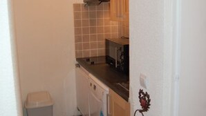 A compact kitchen with a dishwasher, a small trash bin, and a microwave. - Charming 2-room cabin for 6, ski-in/ski-out access (Avoriaz)