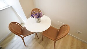 A small round table with a white top and two wicker chairs. A vase with purple flowers is on the table. - La Chicca - Large Suite - Matera (Matera)