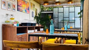 A restaurant with a thatched ceiling, wooden chairs with yellow cushions, and a black and white patterned floor. - Respira Villaas (Calangute)
