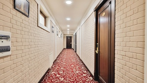 Un pasillo de hotel con paredes de ladrillo, alfombra roja y puertas de madera.