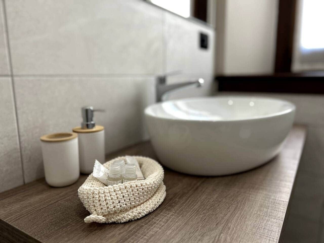 A bathroom with a round sink, a wooden countertop, and two small containers with lids.