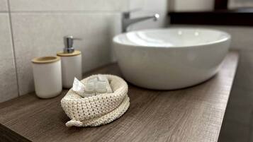 A bathroom with a round sink, a wooden countertop, and two small containers with lids.