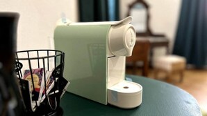 A room with a green table, a white device on it, a black remote control, and a black wire basket with papers. - Stanza d'epoca (Volta Mantovana) Stanza in dimora two steps from Lake Garda (Volta Mantovana)