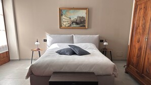 A neatly arranged bedroom with a large bed, two bedside tables with lamps, a wooden wardrobe, and a painting on the wall. - 3-Room with fireplace (Dwelling 1848-Volta Mantovana) (Volta Mantovana)