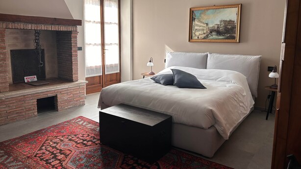 A bedroom with a bed, a fireplace, a painting, and a rug. - 3-Room with fireplace (Dwelling 1848-Volta Mantovana) (Volta Mantovana)