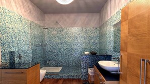 Een moderne badkamer met een wand van mozaïektegels, een houten wastafelmeubel, een witte wasbak en een bad.