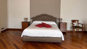 Een netjes ingerichte slaapkamer met een groot bed, twee nachtkastjes, een stoel en een houten vloer.