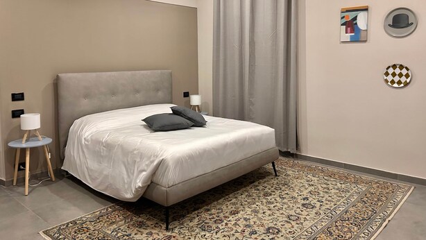 A modern bedroom with a large bed, a patterned rug, and a minimalist decor. - 4-Pop room (Dwelling 1848-Volta Mantovana) (Volta Mantovana)