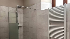 A shower area with a glass door, a white towel rack, and tiled walls. - 4-Pop room (Dwelling 1848-Volta Mantovana) (Volta Mantovana)
