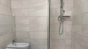 Un baño con ducha, bidé e inodoro.
