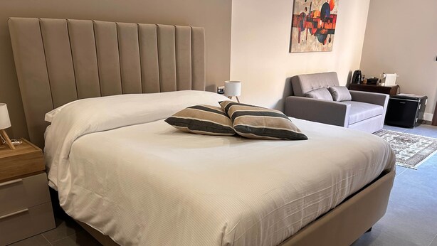 Un dormitorio moderno con una cama grande, una mesita de noche, una lámpara y un cuadro en la pared.