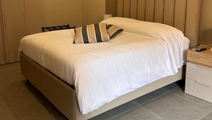 Un dormitorio moderno con una cama grande, una mesita de noche de madera y una mesilla auxiliar.