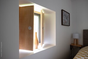 Une chambre d’hôtel avec une porte en bois, une table de chevet avec une lampe et un tableau encadré au mur.