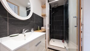 Ein modernes Badezimmer mit einem Doppelwaschbecken, einer Duschkabine aus Glas und einem großen Spiegel.
