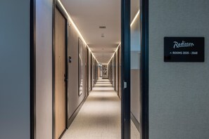 A hotel corridor with doors on both sides, a sign indicating rooms 2035-2068, and a patterned wall at the end. - Radisson Hotel Amsterdam Airport Schiphol Hoofddorp (Hoofddorp)