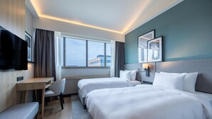 A hotel room with two beds, a desk, a chair, a TV, and a window with a view of buildings. - Radisson Hotel Amsterdam Airport Schiphol Hoofddorp (Hoofddorp)